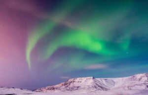 The Northern Lights over a snowy mountain in Iceland