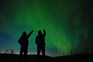 Two people silhouetted by the Northern Lights in Iceland 