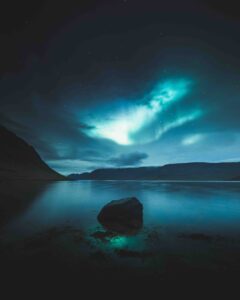 The Northern Lights over a lake in Iceland between the clouds