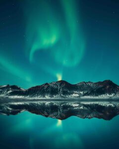 The Northern Lights over a mountain range in Iceland