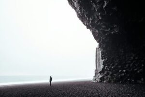 A person standing on Reynisfjara black sand beach in Iceland
