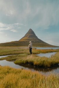 A traveller standing in front of Kirkjufell mountain in Iceland's Snæfellsnes peninsula during summer