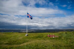 The Icelandic flag flying at the edge of a fjord in Iceland during Iceland's National Day
