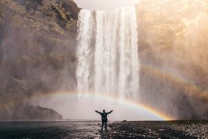 A person standing underneath Skogafoss waterfall in Iceland