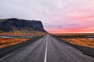 The open road in Iceland with a mountain under the Midnight Sun ahead