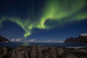 The aurora borealis dancing over the sea and mountains in Iceland during winter