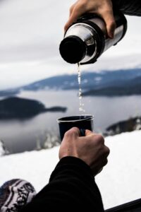 People having a drink from a warm flask in Iceland in the snow