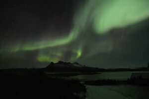 The Northern Lights shining in over a mountain in Iceland