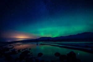 The Northern Lights over a mountain in Iceland under a sky full of stars