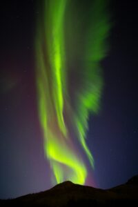 A Northern Lights corona dancing over a mountain in Iceland