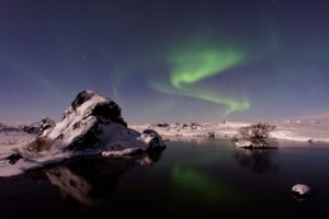 The Northern Lights in Iceland over a snowy landscape and lake