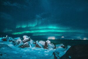 The Northern Lights over a snow-covered landscape in South Iceland