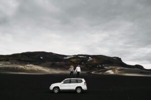 A couple standing on top of their rental car in Iceland