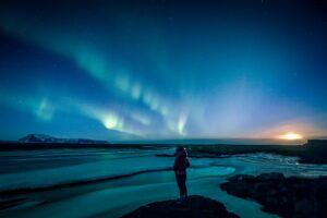 A girl standing under the Northern Lights in Iceland in August